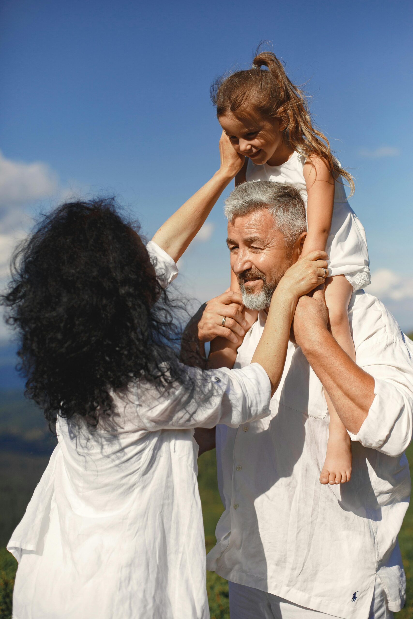 Grandparents playing with granddaughter outdoors, enjoying sunny day